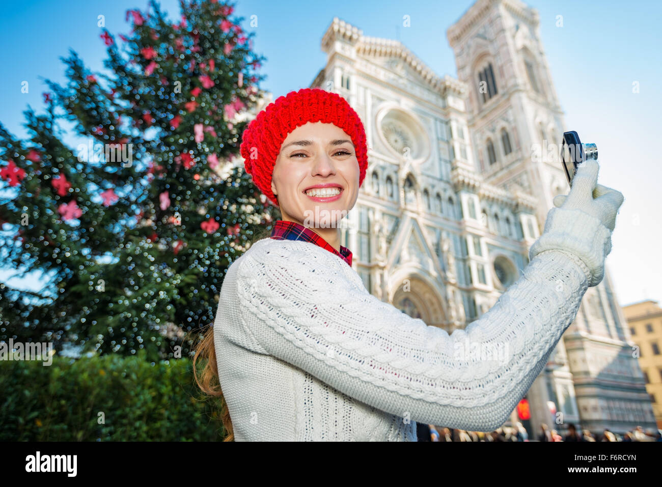 Felice traveler donna prendendo foto nel centro storico di Firenze mentre in piedi nella parte anteriore del tradizionale albero di Natale vicino al Duomo Foto Stock