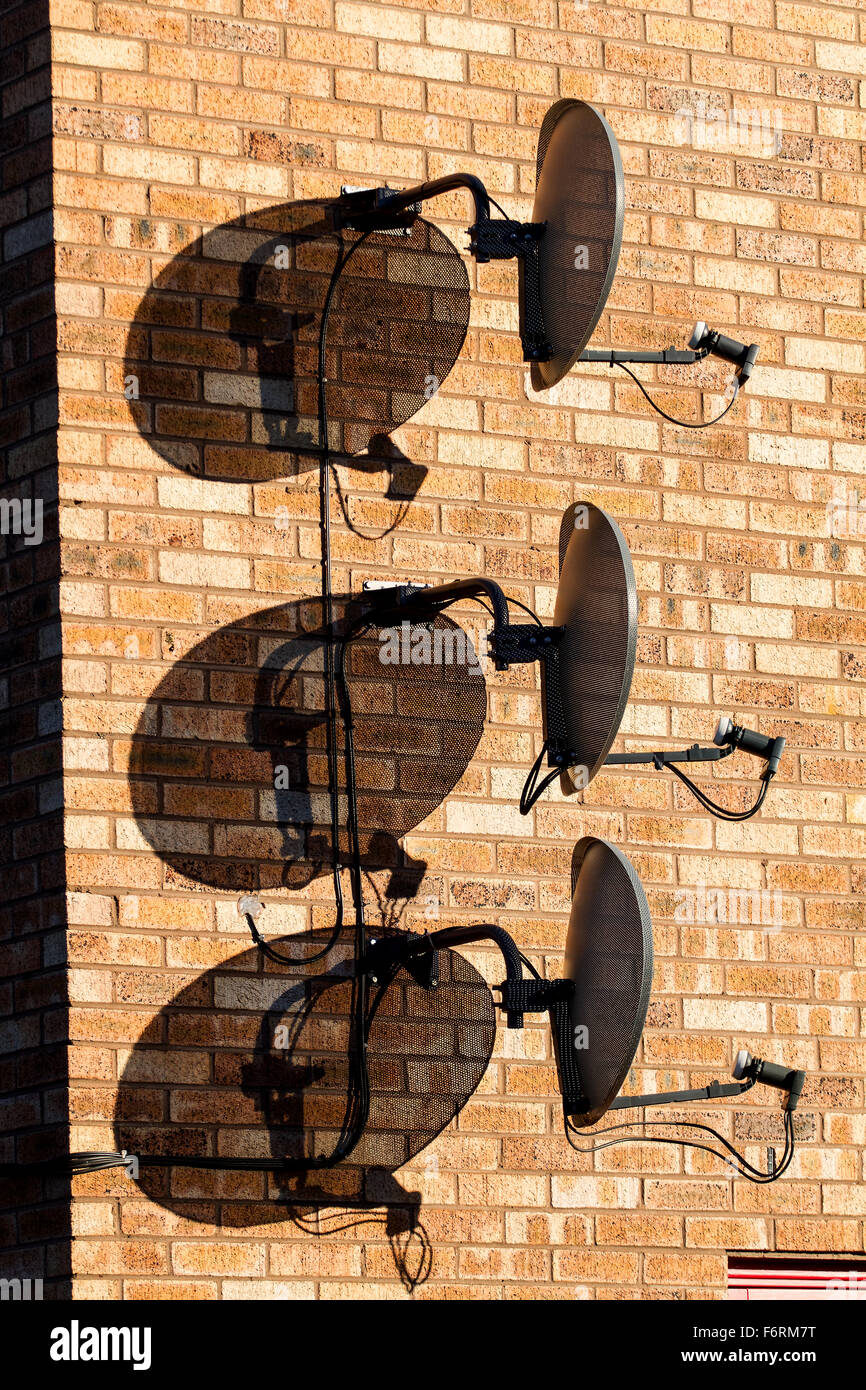 Tre Sky TV satellite digitale piatti insieme fissato verticalmente al di sopra di ogni altro su di un moderno muro di casa a Dundee, Regno Unito Foto Stock