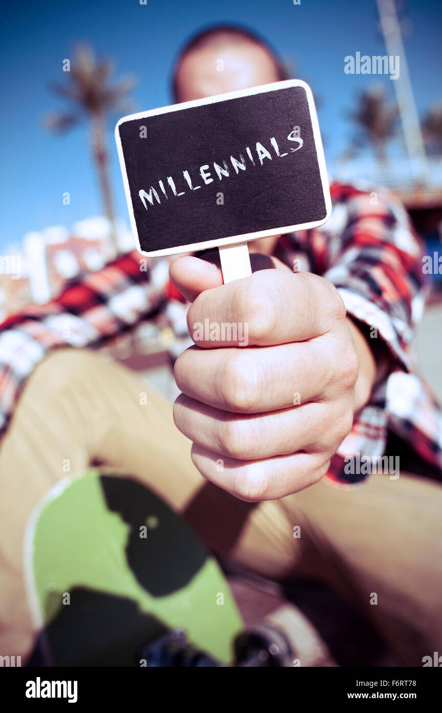 Un giovane pattinatore caucasica all'aperto mostra un cartello con scritto il testo millennial scritto in esso Foto Stock