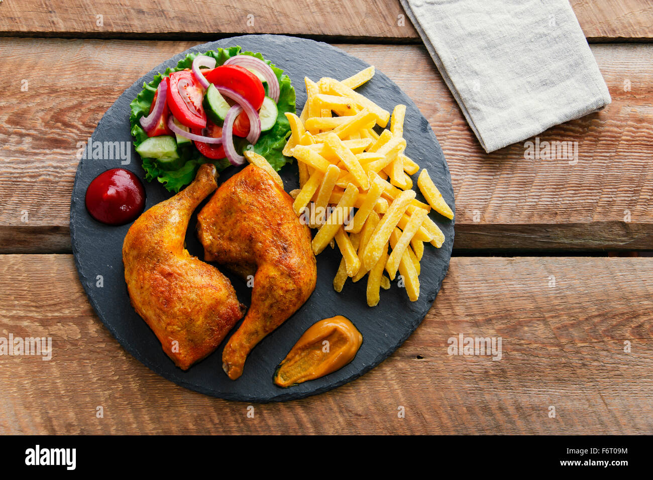 Arrosto di cosce di pollo con patatine fritte e insalata mista Foto Stock