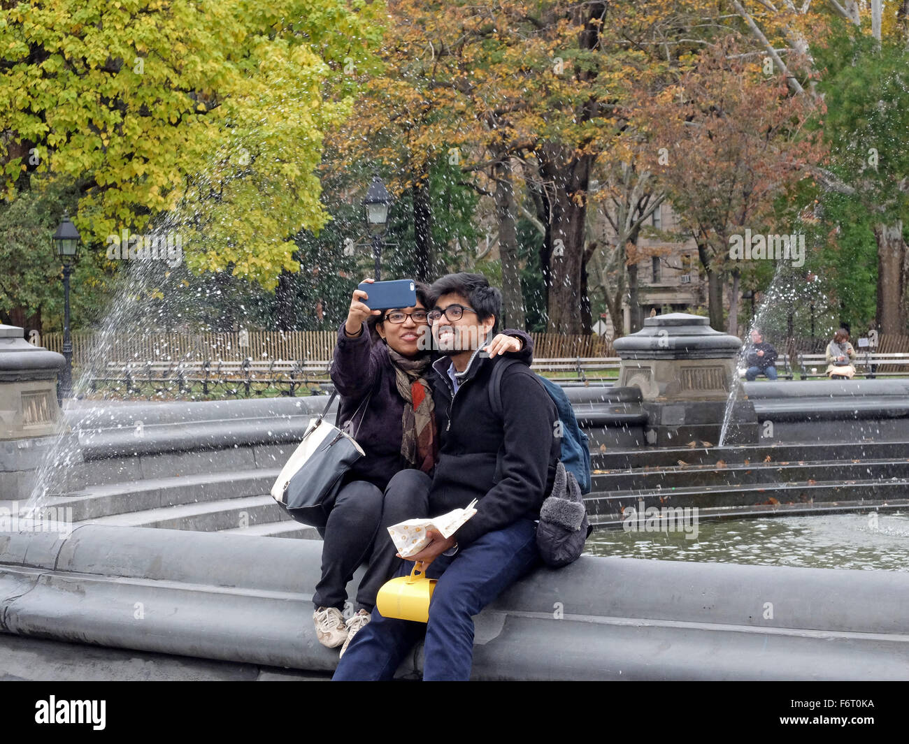 Una coppia attraente prendendo un selfie vicino alla fontana di Washington Square Park nel Greenwich Village di New York City Foto Stock