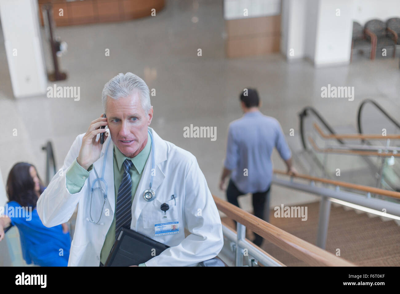 Medico parlando al cellulare su gradini Foto Stock