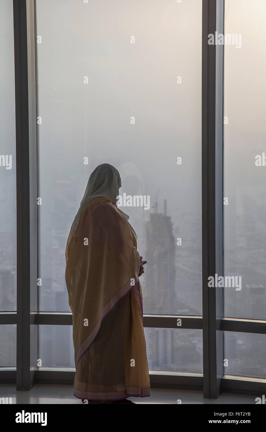 Donna asiatica in corrispondenza della finestra ammirando Dubai cityscape, Emirato di Dubai, Emirati Arabi Uniti Foto Stock