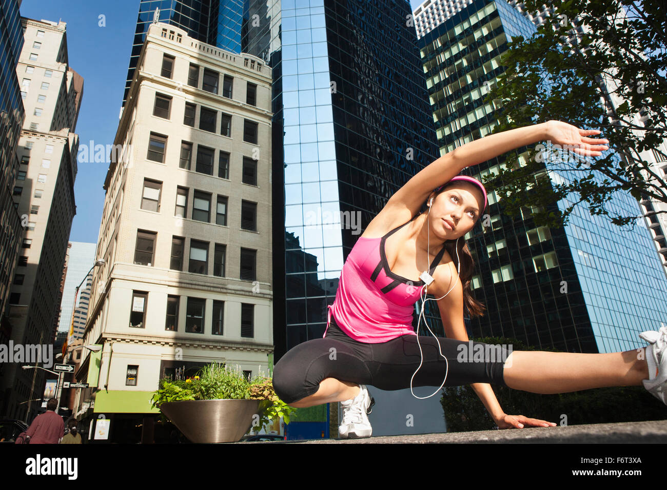 Donna ispanica stretching sotto il grattacielo di edifici Foto Stock