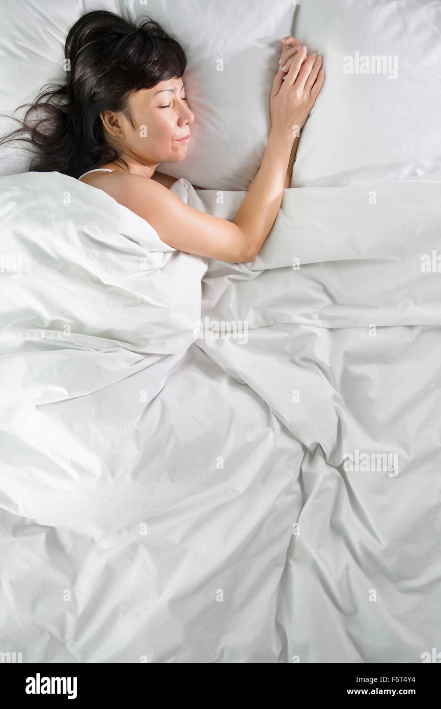 Razza mista donna che dorme nel letto Foto Stock