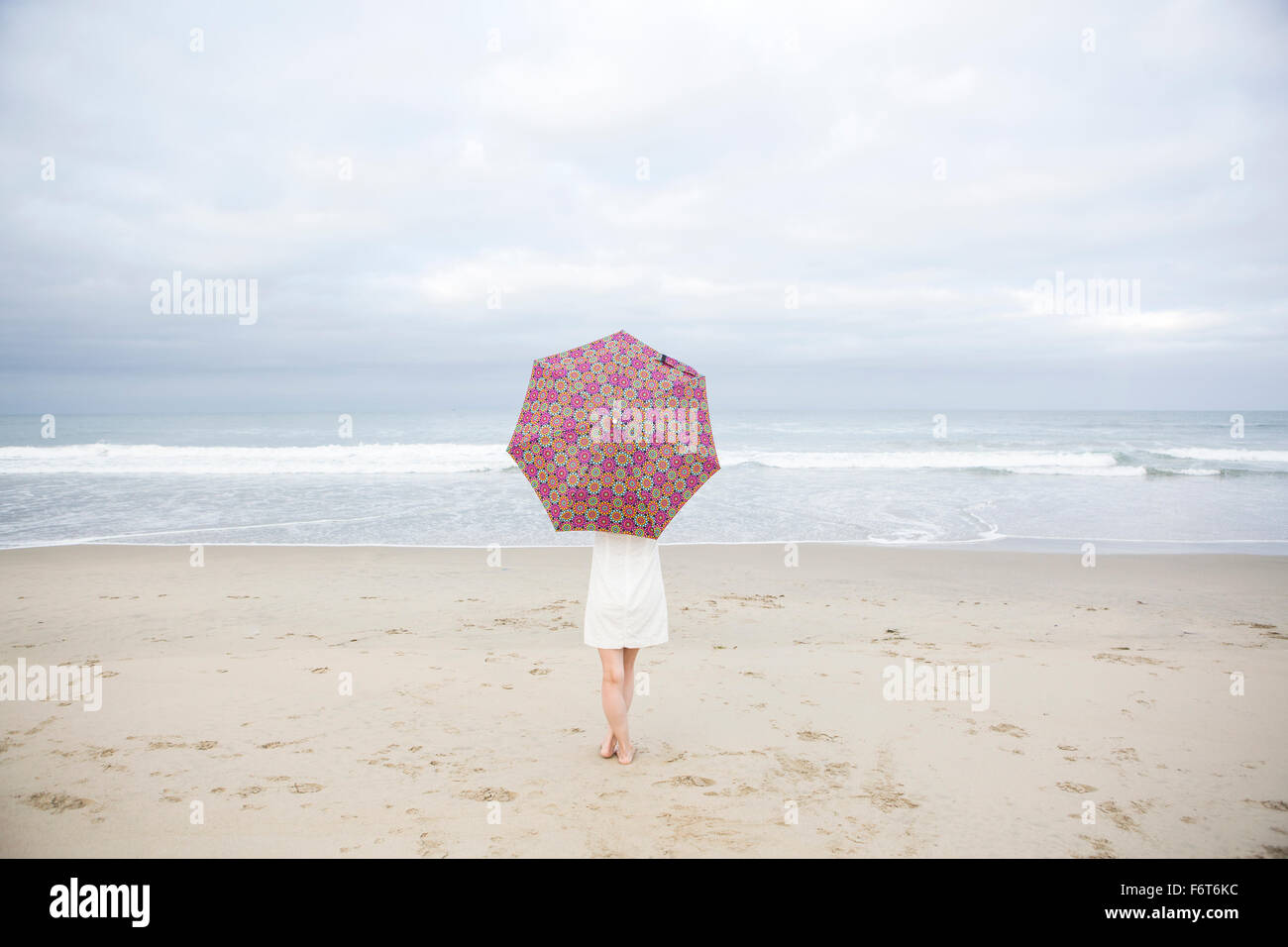 Donna con ombrellone in spiaggia Foto Stock