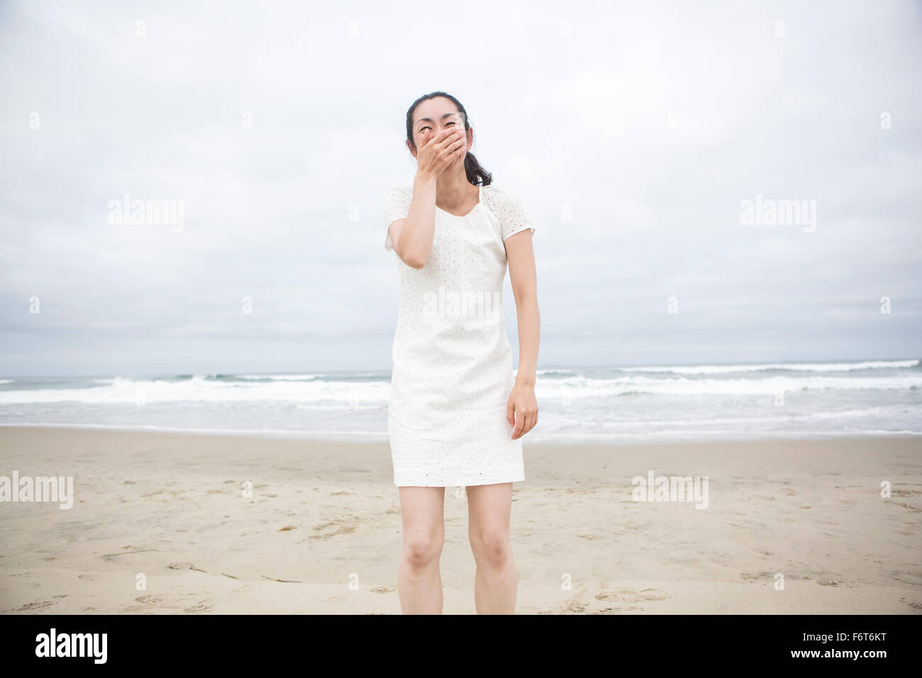 Donna che ride sulla spiaggia Foto Stock
