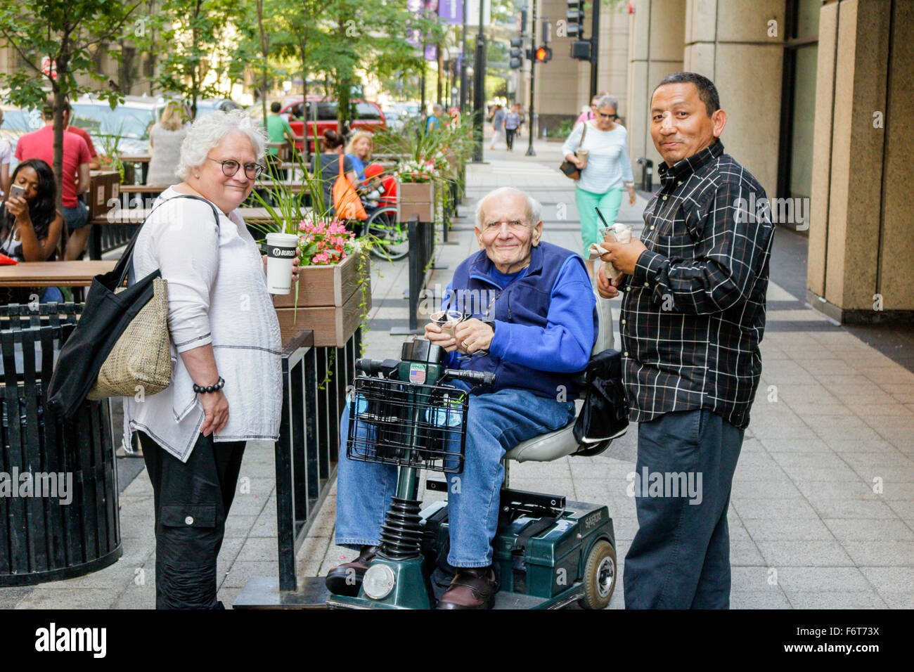 Uomo anziano su scooter elettrico con un altro uomo e donna. Chicago, Illinois. Foto Stock