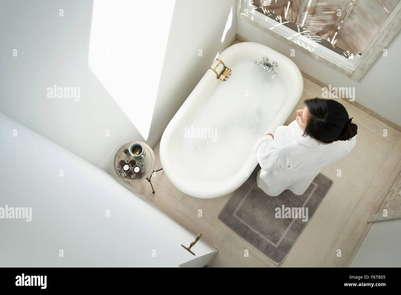 Donna con bolla bagno nella stanza da bagno Foto Stock