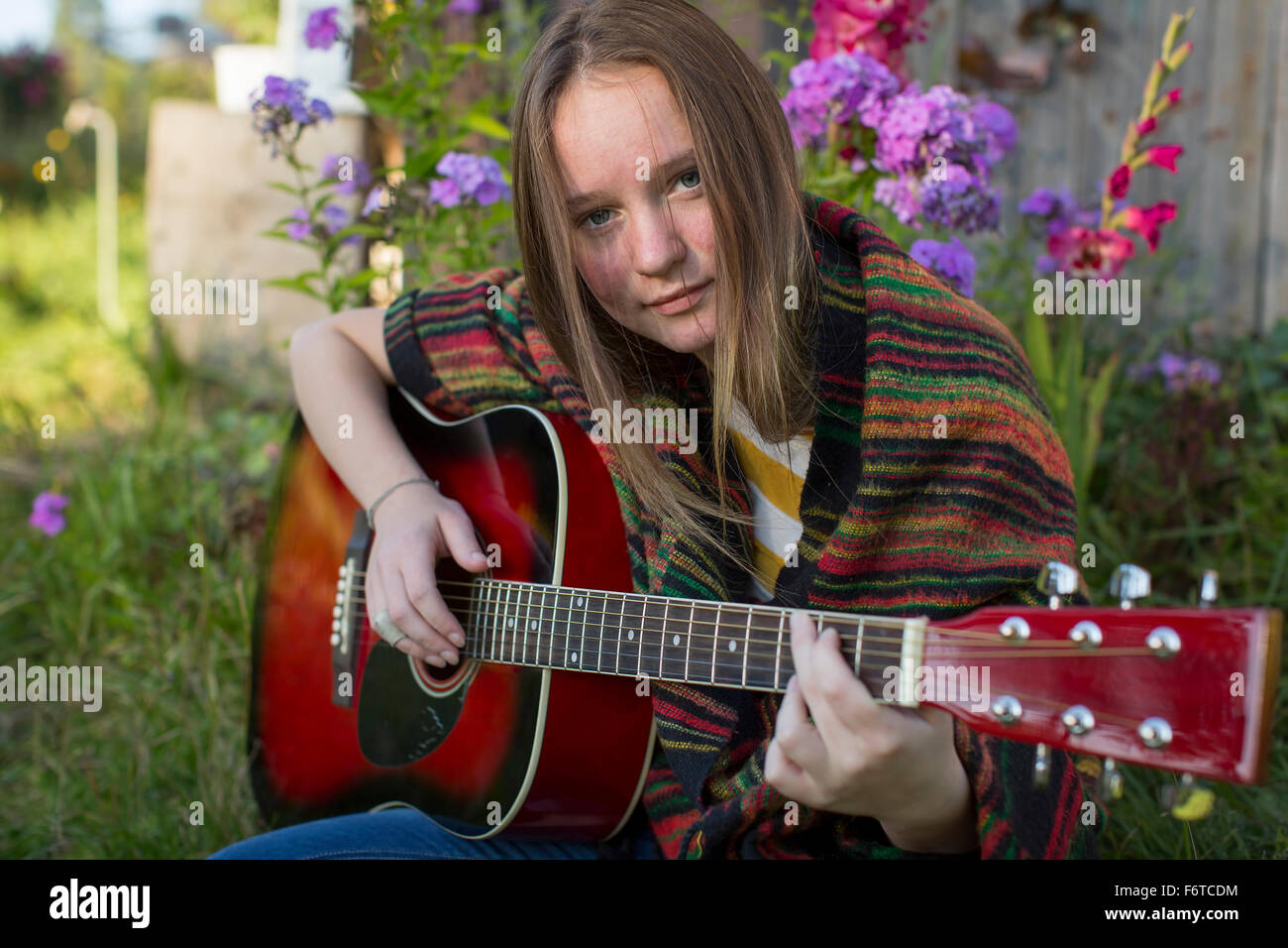 Una ragazza adolescente suonare la chitarra acustica all'esterno. Foto Stock