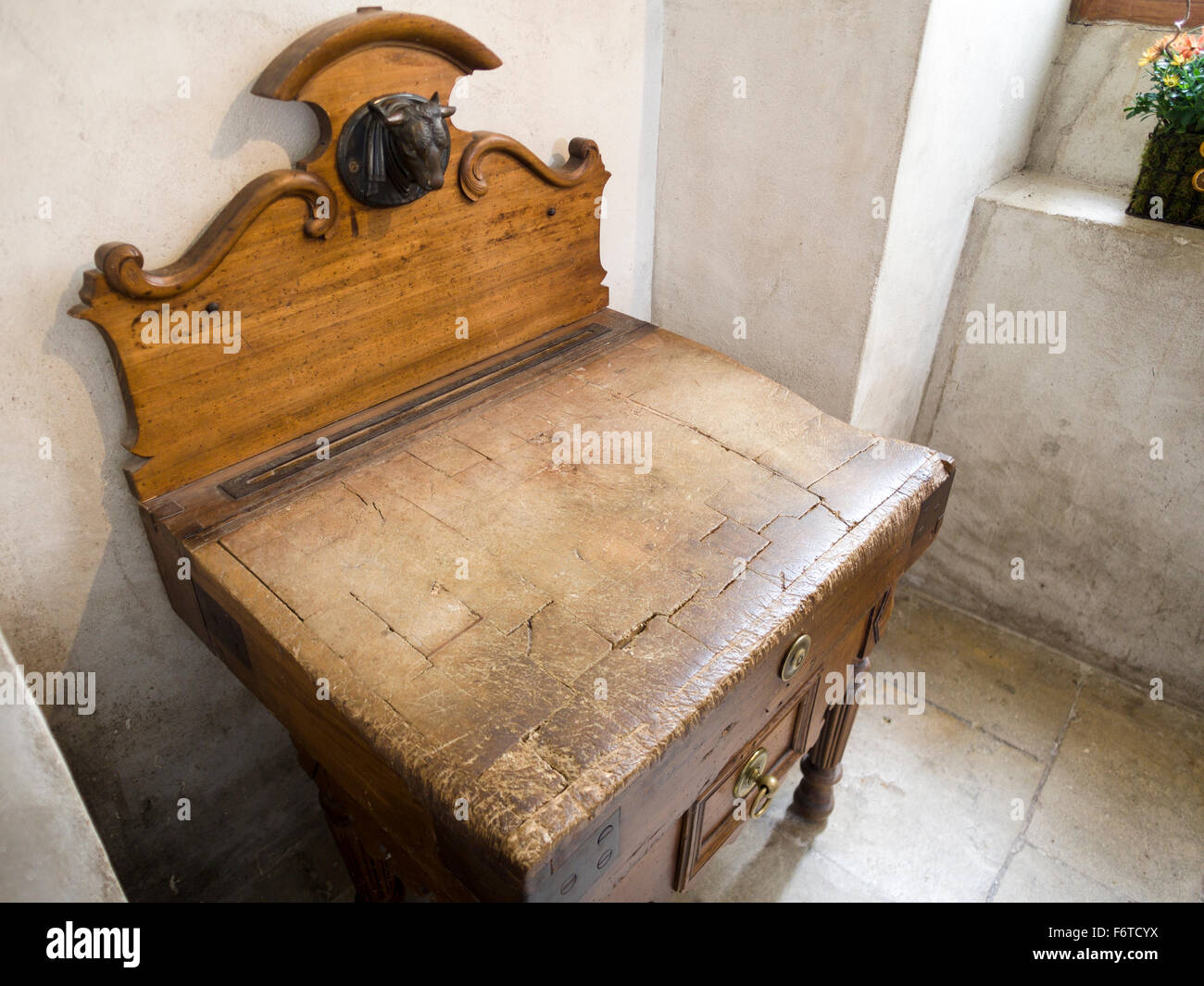 Ben utilizzati in legno del macellaio di blocco. Un bronzo testa di mucche che non lascia alcun dubbio per quanto riguarda lo scopo di questo ben indossati tagliere Foto Stock