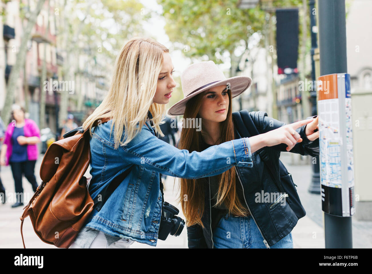 Spagna, Barcellona, due giovani donne guardando una mappa della città in pole Foto Stock