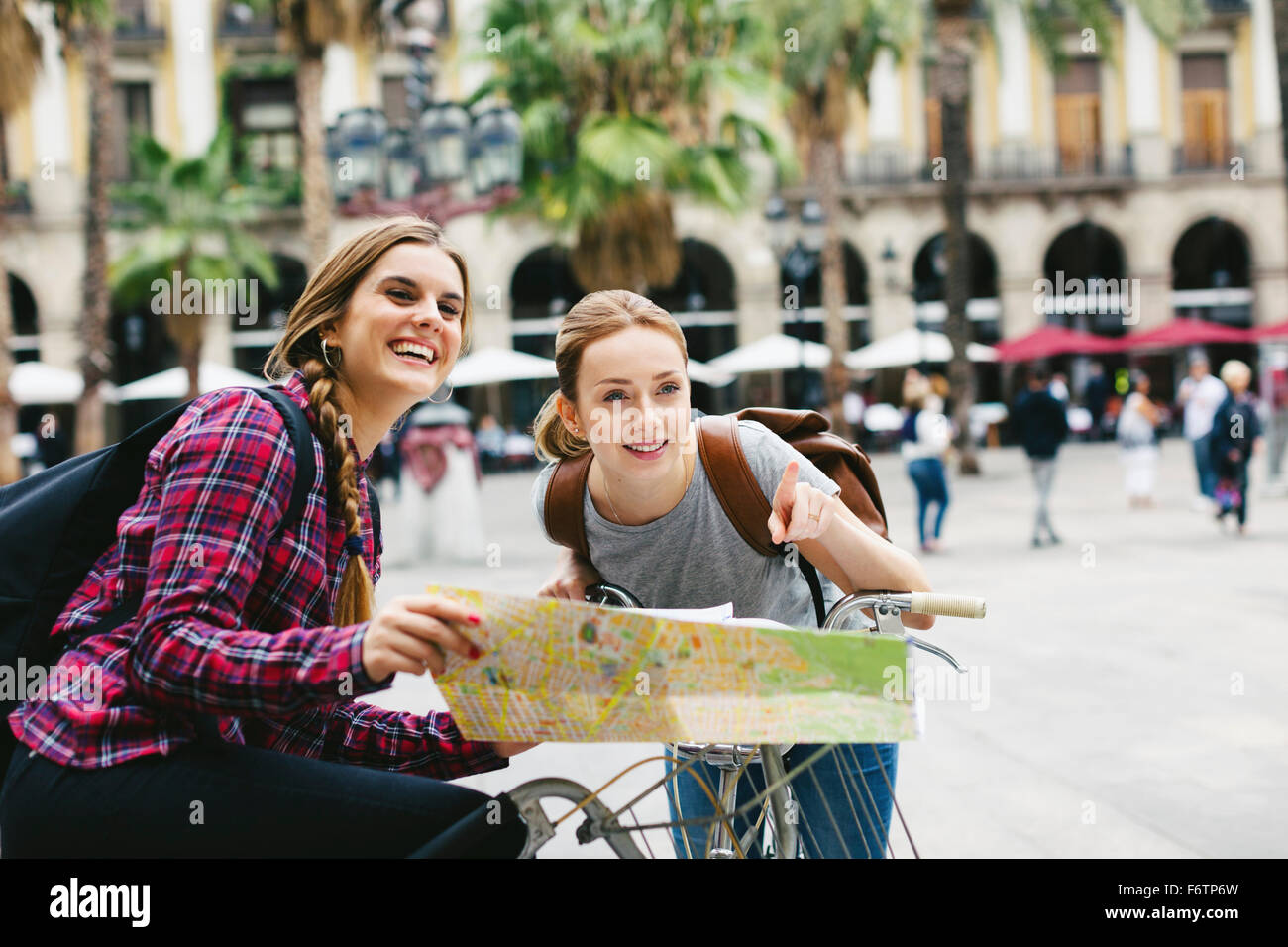 Spagna, Barcellona, due giovani donne con mappa su biciclette in città Foto Stock