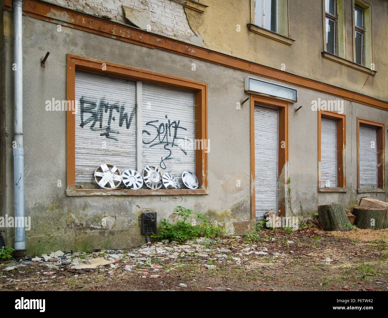 Viste oblique della vecchia facciata marcio con persiane chiuse e la vecchia Coppa ruote allineate Foto Stock