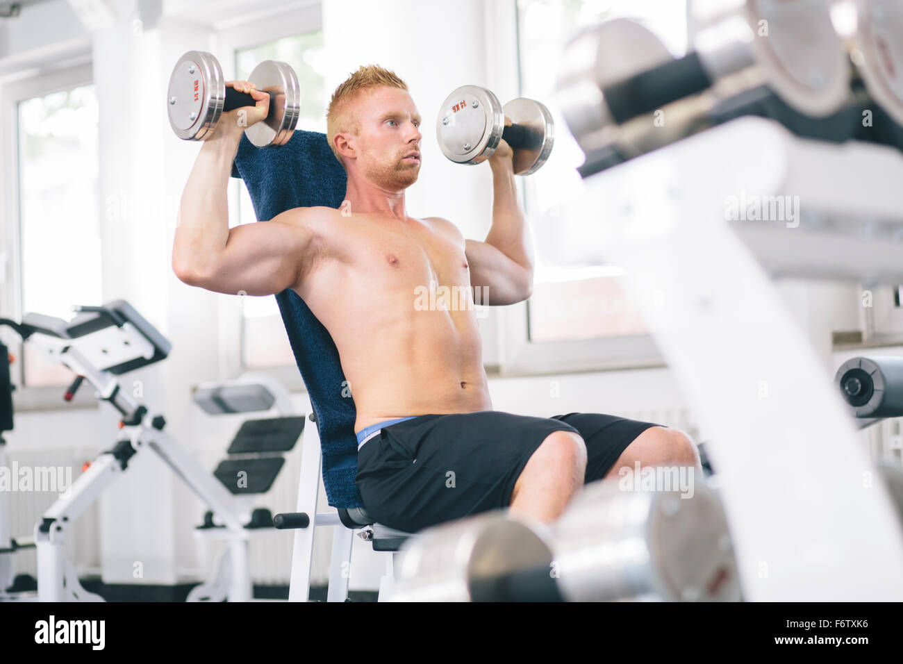 Atleta fisico esercizio con manubri Foto Stock