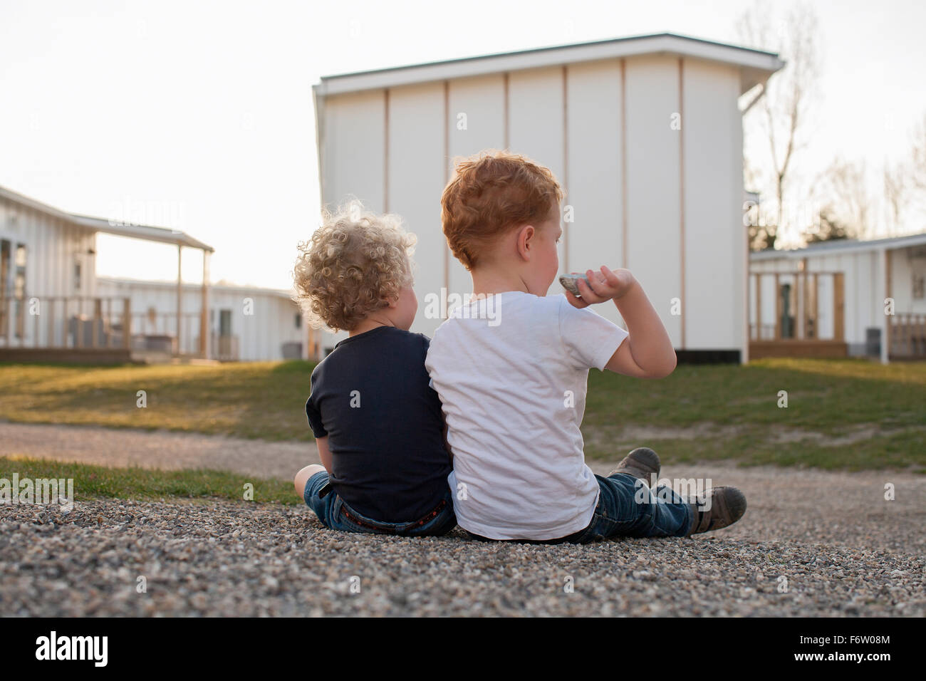 Bambina e ragazzo seduto sul sentiero di ghiaia Foto Stock