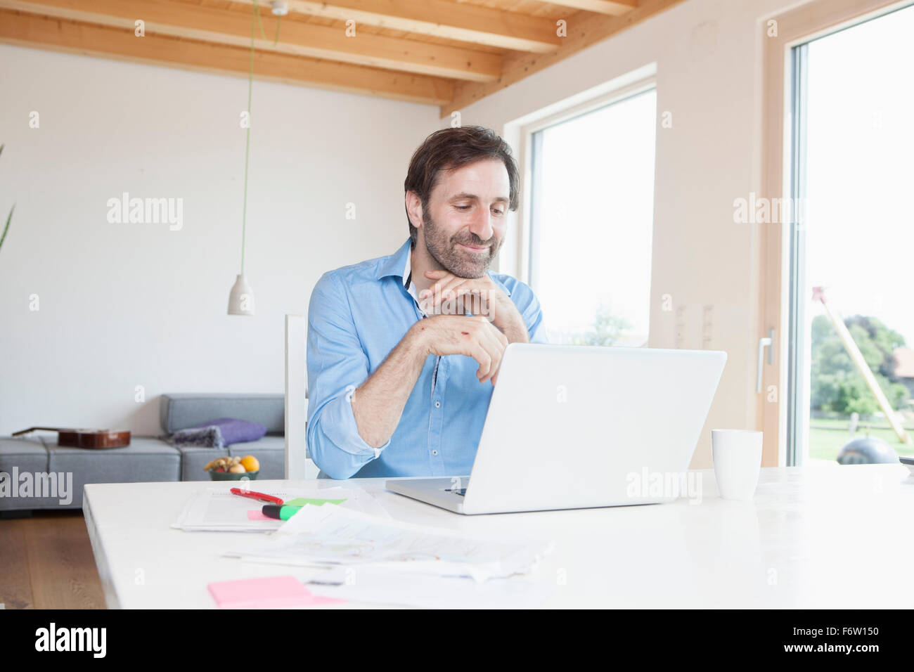 Uomo maturo lavorando da casa, utilizzando laptop Foto Stock
