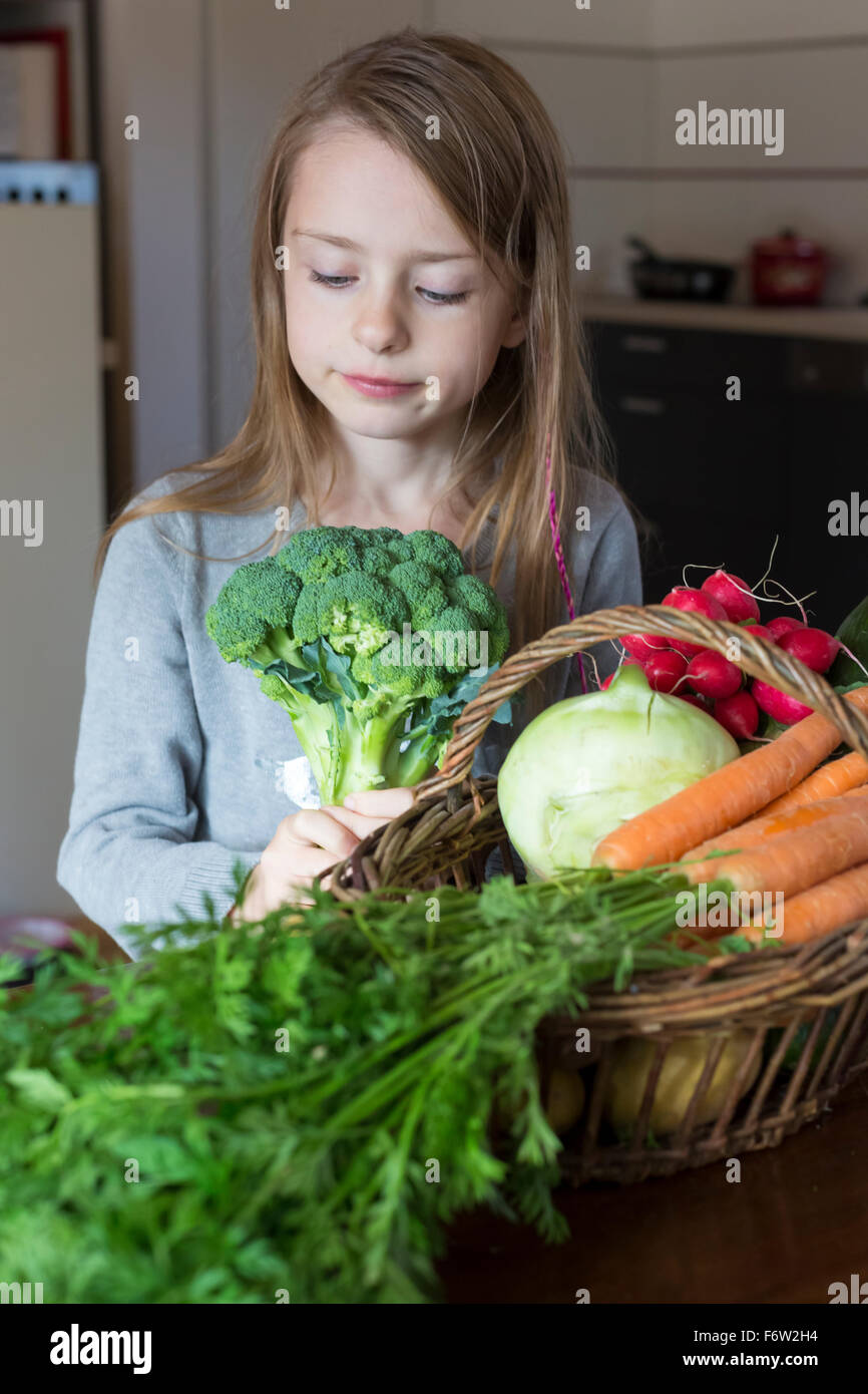 Ritratto di ragazza con wiccurbasket di verdure fresche guardando i broccoli Foto Stock