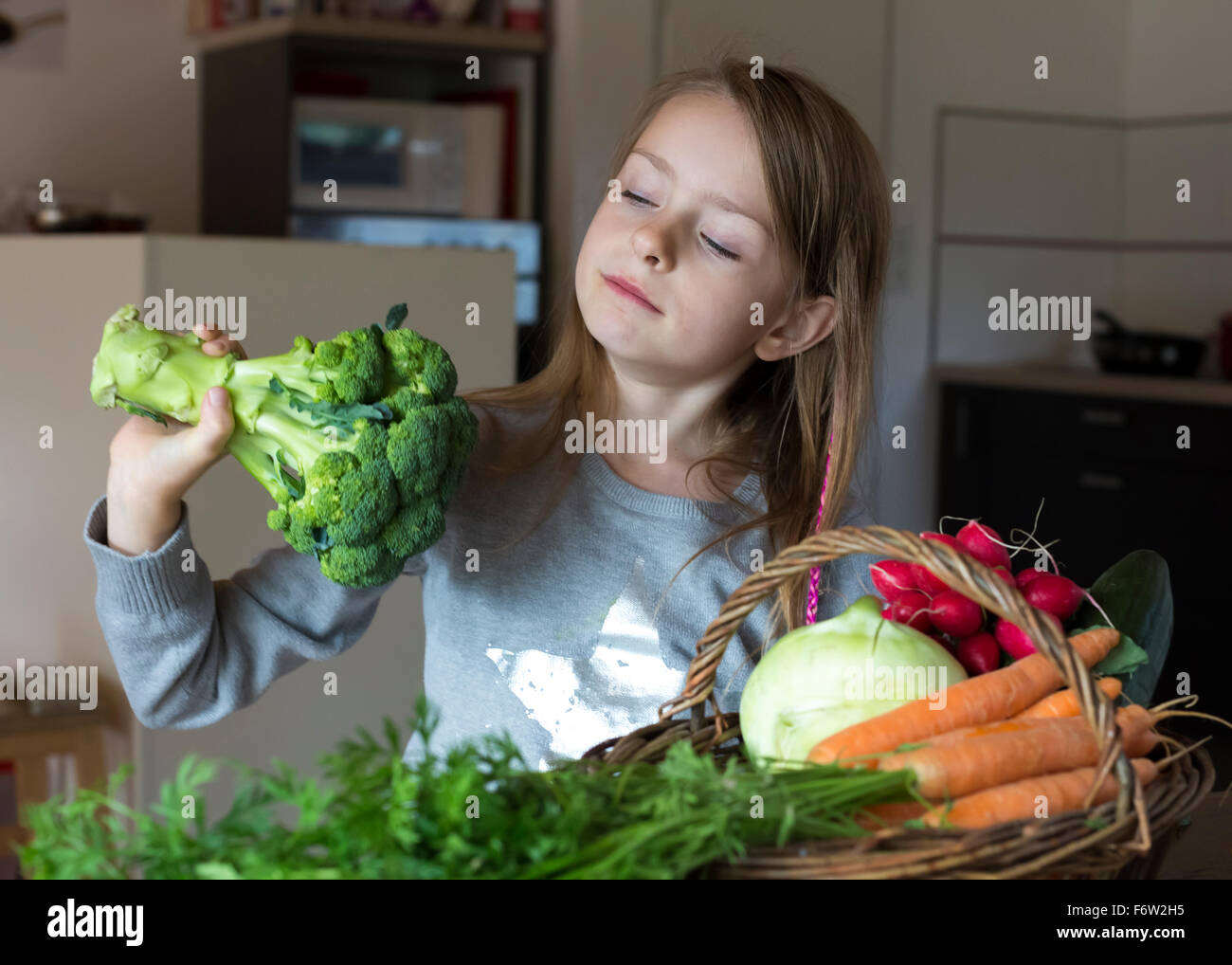 Ritratto di ragazza con wiccurbasket di verdure fresche guardando i broccoli Foto Stock