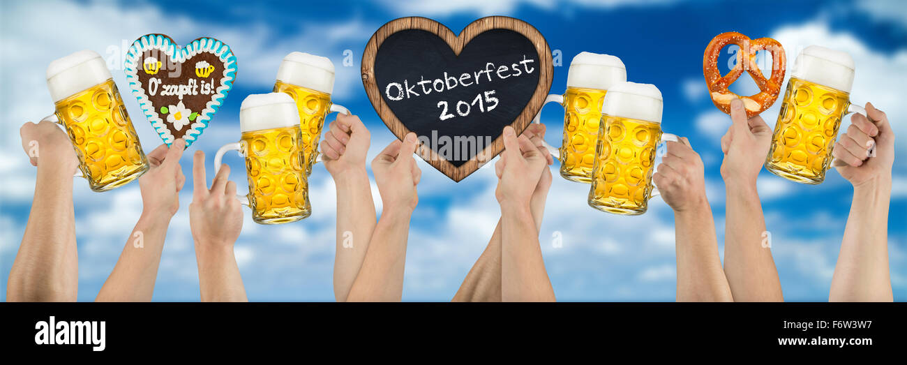 Molte mani azienda tedesca birra Oktoberfest a forma di cuore e di panpepato blackboard su blu cielo molto nuvoloso Foto Stock