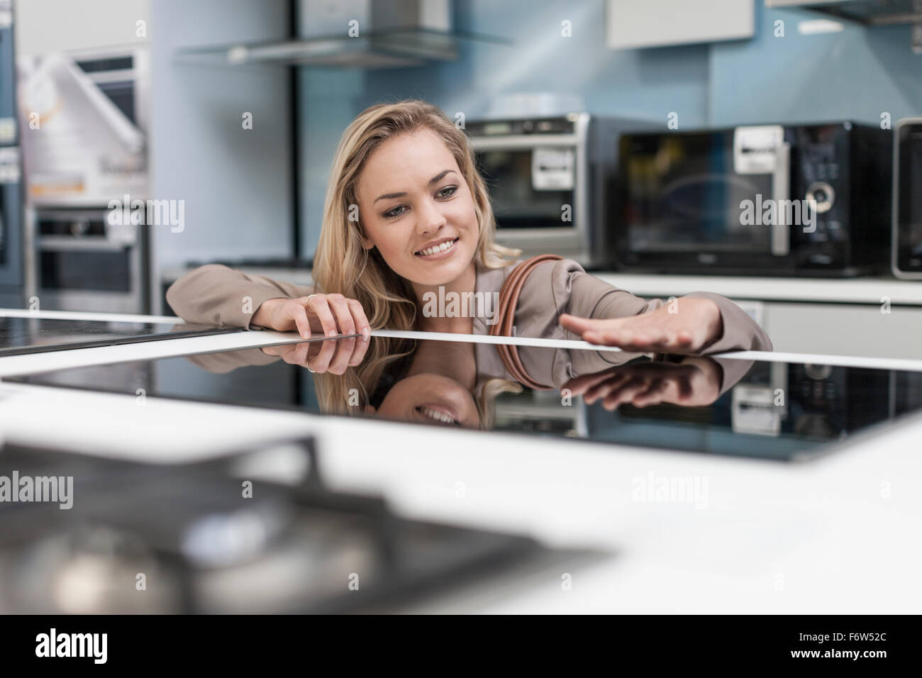 Giovane donna esame fornello ad induzione in un negozio Foto Stock