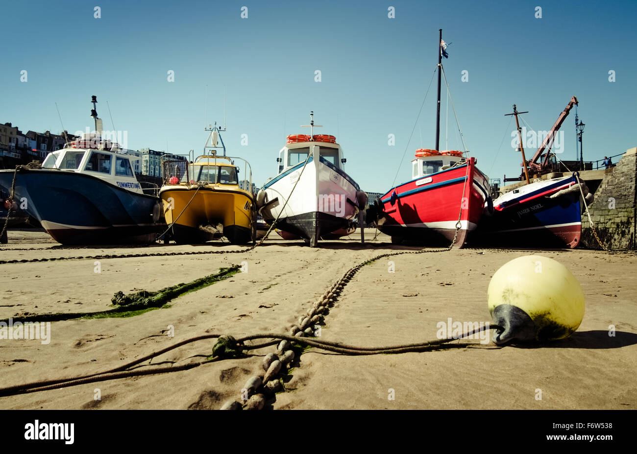 Cinque barche colorate ormeggiata in porto a bassa marea,in un pomeriggio soleggiato, Tenby, Pembrokeshire, Wales, Regno Unito. Foto Stock