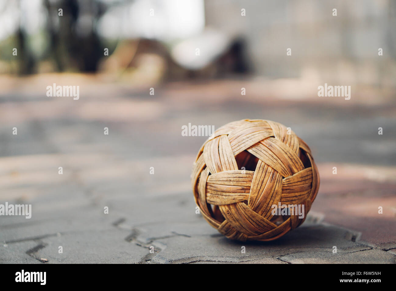 Sepak takraw palla sul pavimento piastrellato con mattoni di spazio copia, sfondo sfocato. il sud est asiatico famoso locale di sport o di attività asiatiche concept Foto Stock