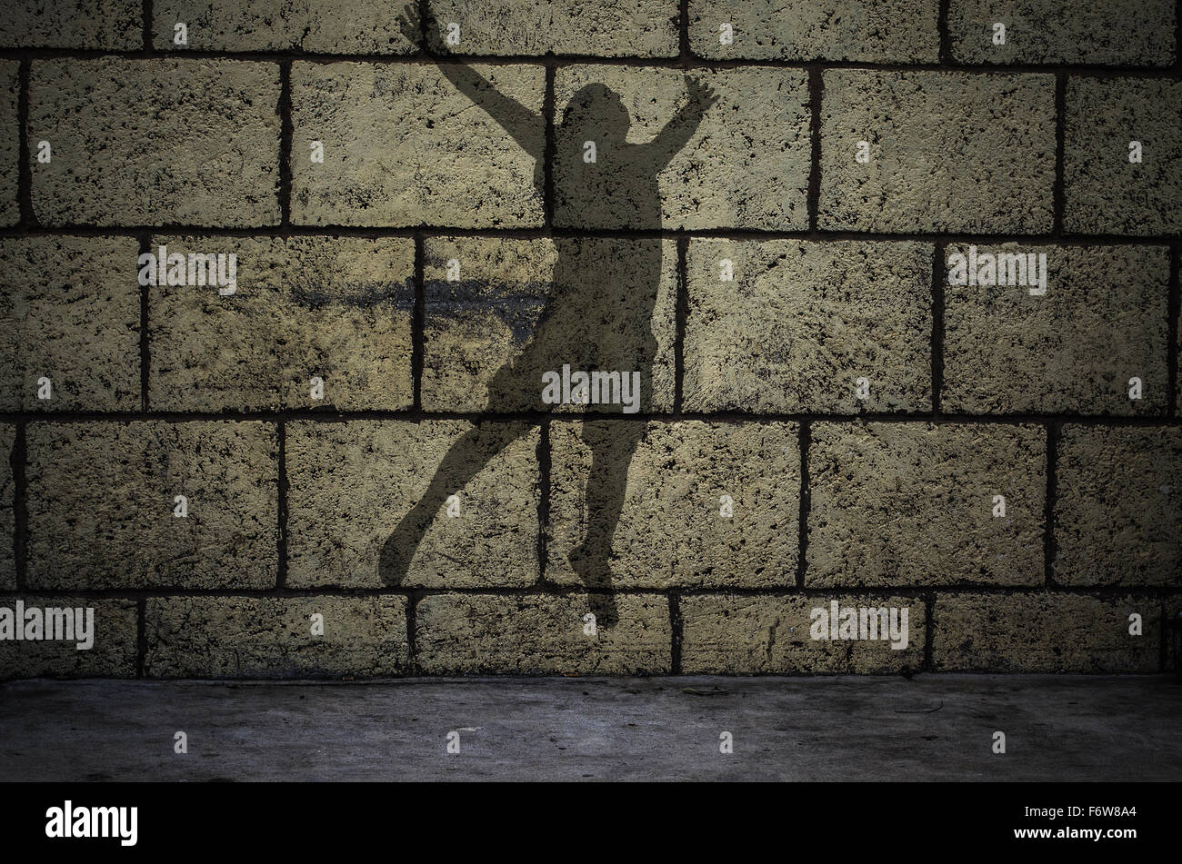 Silhouette uomo saltando di fronte al muro di mattoni Foto Stock