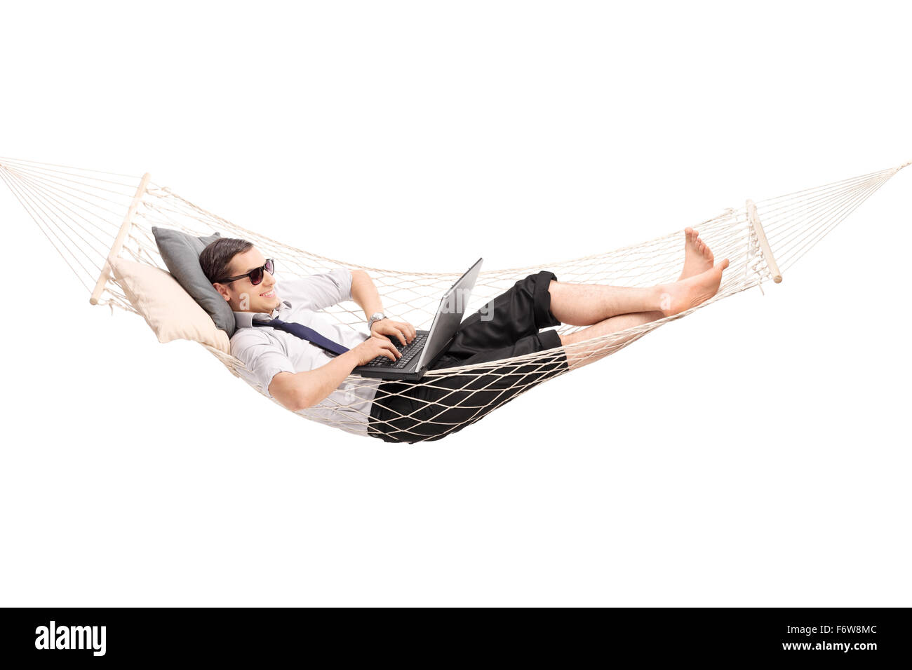 Giovane imprenditore spensierata lavorando su laptop e giacente in una amaca isolati su sfondo bianco Foto Stock