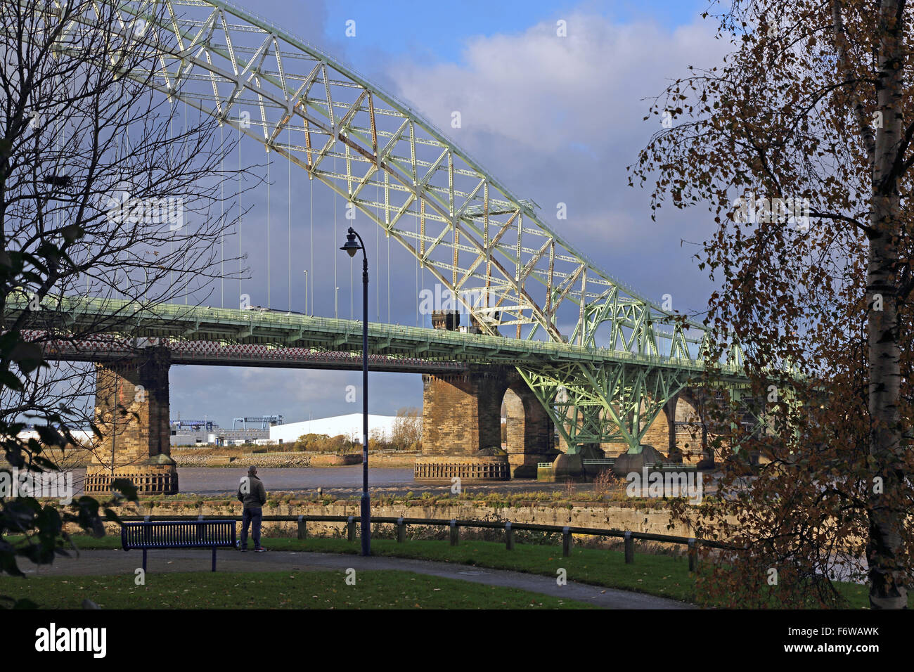 Un uomo guarda il Giubileo d'argento ponte che attraversa il fiume Mersey a Runcorn, Cheshire, Regno Unito Foto Stock