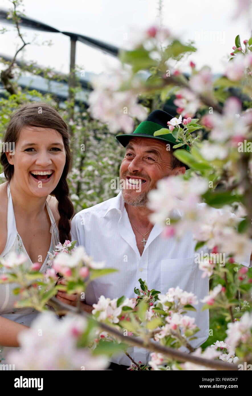 Giovane donna e frutta agricoltore tra fioriti alberi di mele, Riegersburg, Stiria, Austria Foto Stock