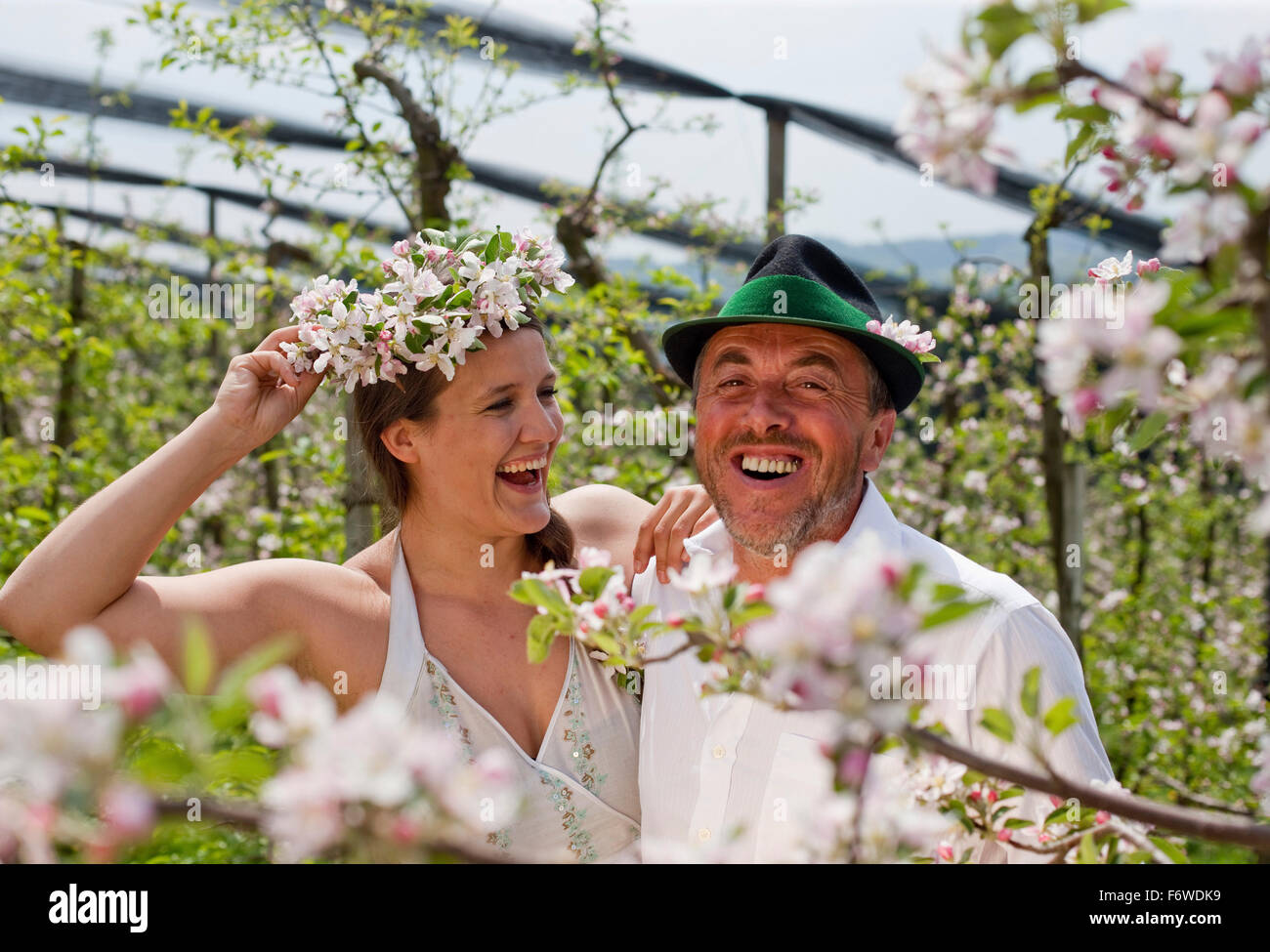 Giovane donna e frutta agricoltore tra fioriti alberi di mele, Riegersburg, Stiria, Austria Foto Stock