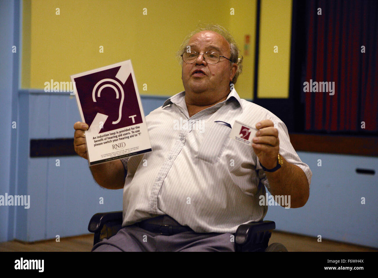 Uomo disabili Relatore a Disability Awareness Forum; mostra loop di induzione segno, Foto Stock