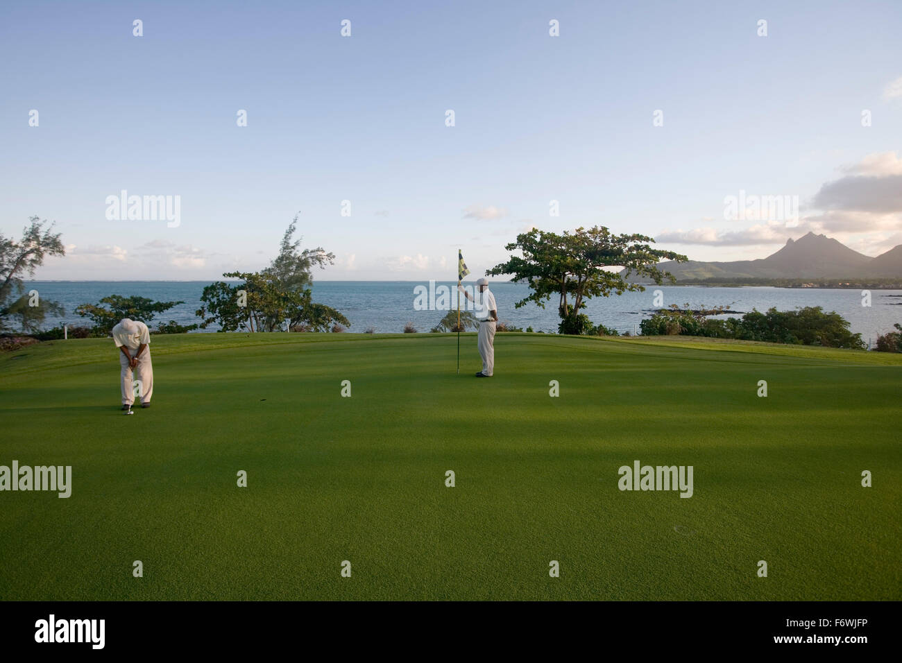 Giocatore di golf putting sul verde del foro 11: giro alla curva del Le Touessrok Golf, Ile aux Cerfs isola vicino Trou d'Eau Douce, Foto Stock