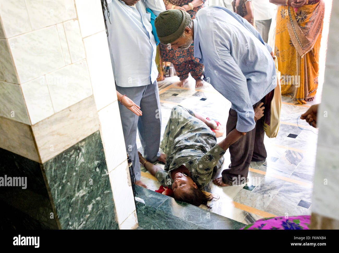 Una donna in stato posseduto che giace di fronte alla namaaz a Bavadavadar dargah , Dadapir viene rilevata da i membri della sua famiglia . Il santuario svolge comprimario a quella principale dedicata al Pir Harjat Syed fino alla strada. shoot Data 05 - 08 Maggio 2010 Foto Stock