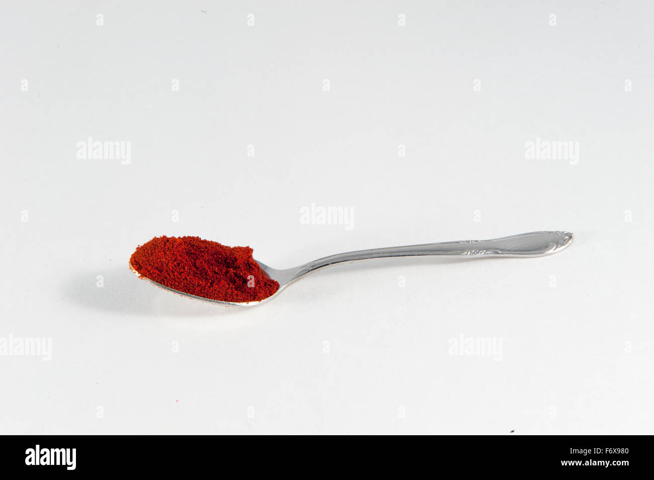 Un cucchiaio di paprika affumicato contro uno sfondo bianco su sfondo bianco Foto Stock