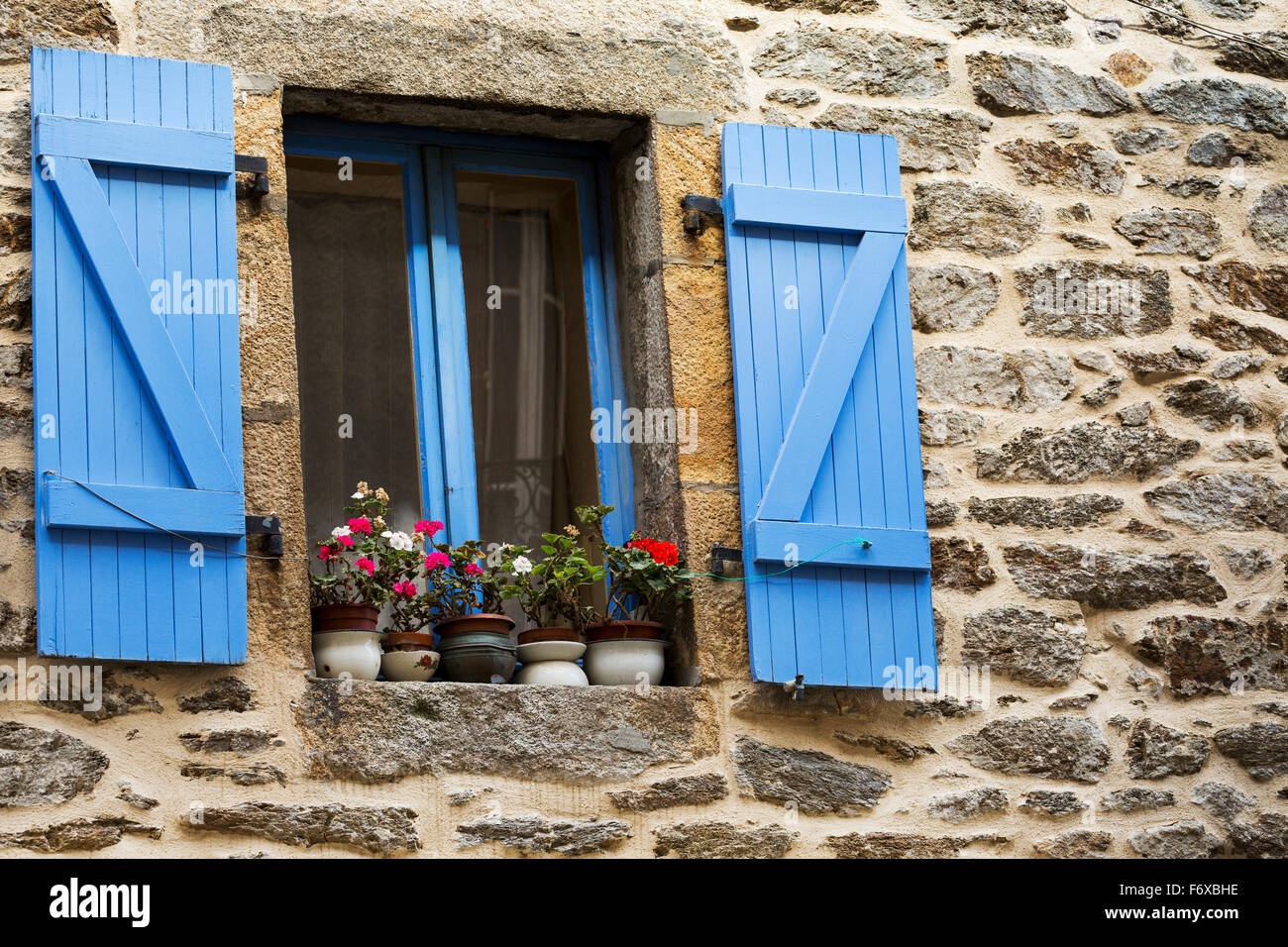 Close up colorfully dipinto di blu scuri e telaio della finestra su un edificio in pietra con vasi di fiori sul davanzale della finestra; Brest, Brittany, Francia Foto Stock