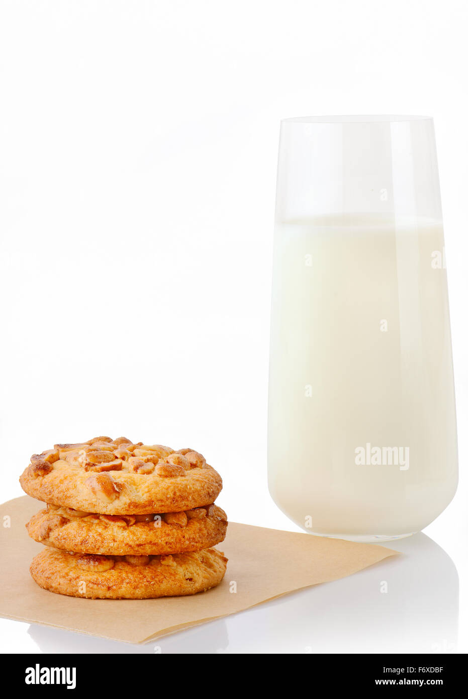 Pila di tre fatti in casa il burro di arachidi cookie sul foglio di carta forno e un bicchiere di latte, isolato su sfondo bianco Foto Stock