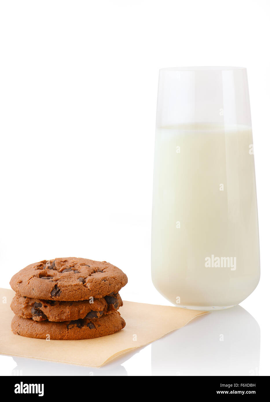 Pila di tre in casa i biscotti al cioccolato sulla carta da forno e un bicchiere di latte, isolato su sfondo bianco Foto Stock