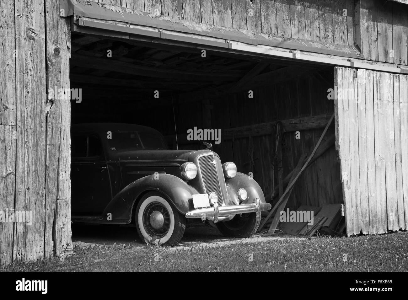 Immagine in bianco e nero del frontale di un antico auto all'interno di un fienile in legno; Frankford, Ontario, Canada Foto Stock