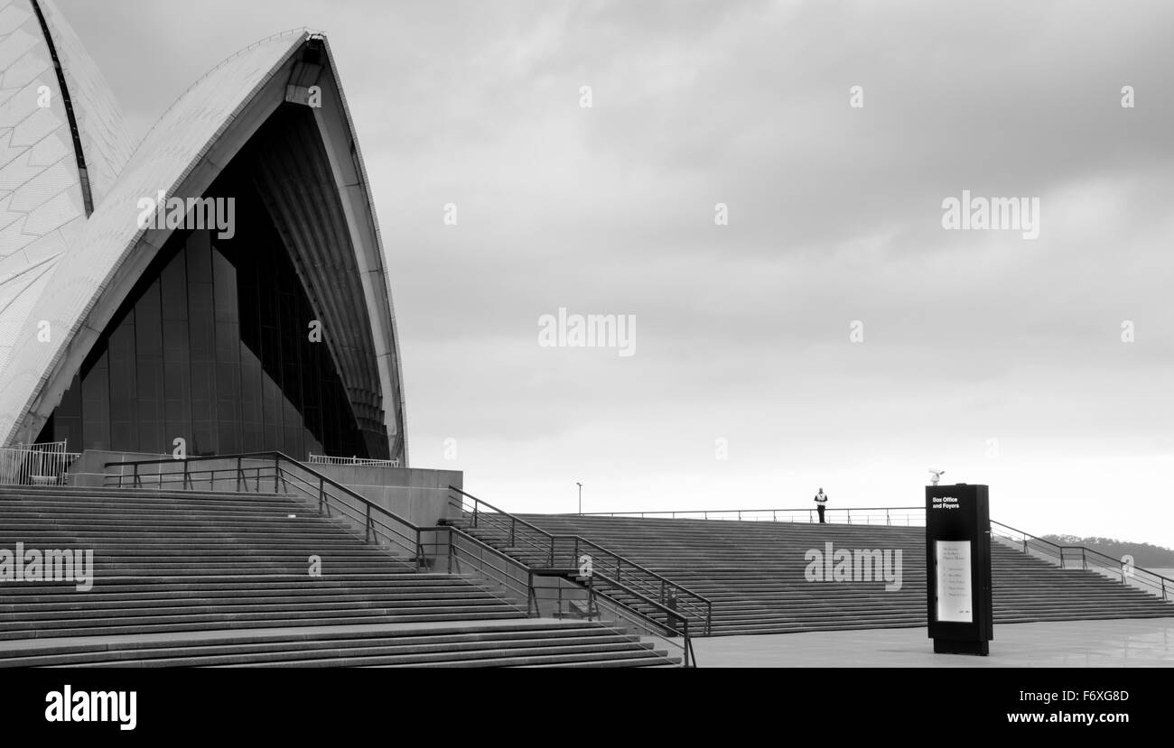 Una sola guardia di sicurezza pattuglia la Sydney Opera House in una giornata nuvolosa in Australia Foto Stock