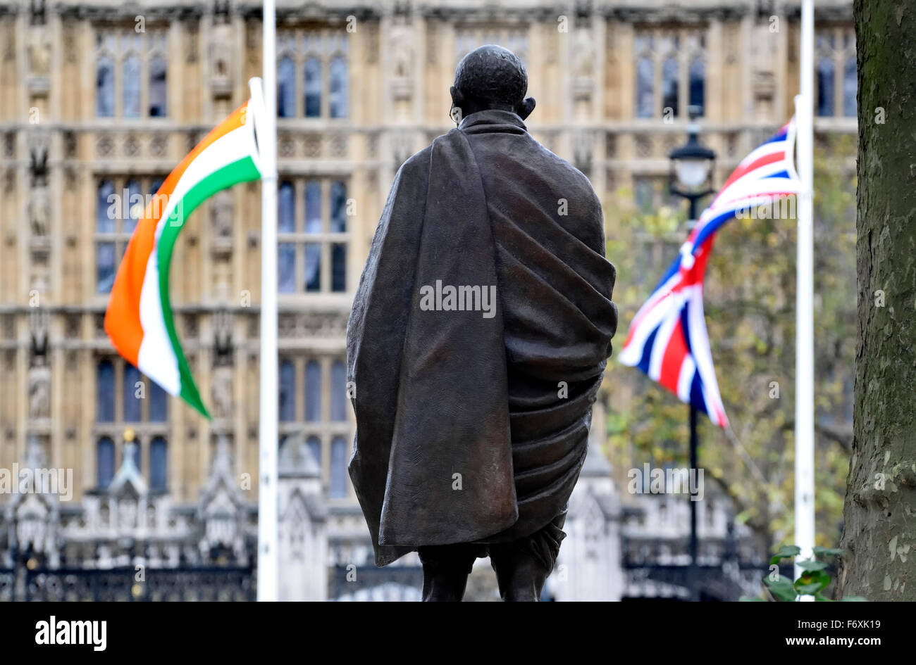 Londra, Inghilterra, Regno Unito. Statua del Mahatma Gandhi, Piazza del Parlamento. (2015: Philip Jackson) con indiani e bandiere britanniche Foto Stock