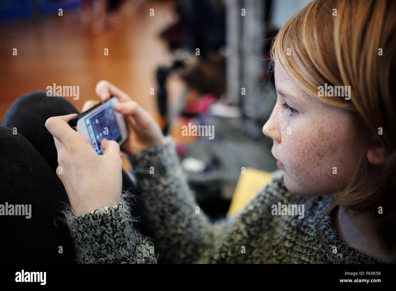 Giovane ragazza bionda la riproduzione su telefono mobile device Foto Stock