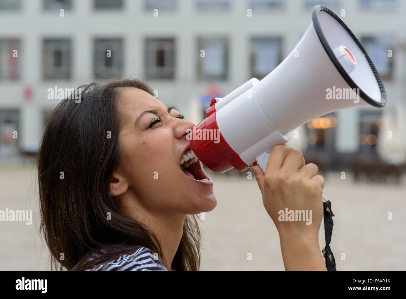 Donna urlare in un bullhorn su una strada urbana esprimendo il suo displaeasure durante una manifestazione di protesta o di dimostrazione, vicino la vista laterale Foto Stock