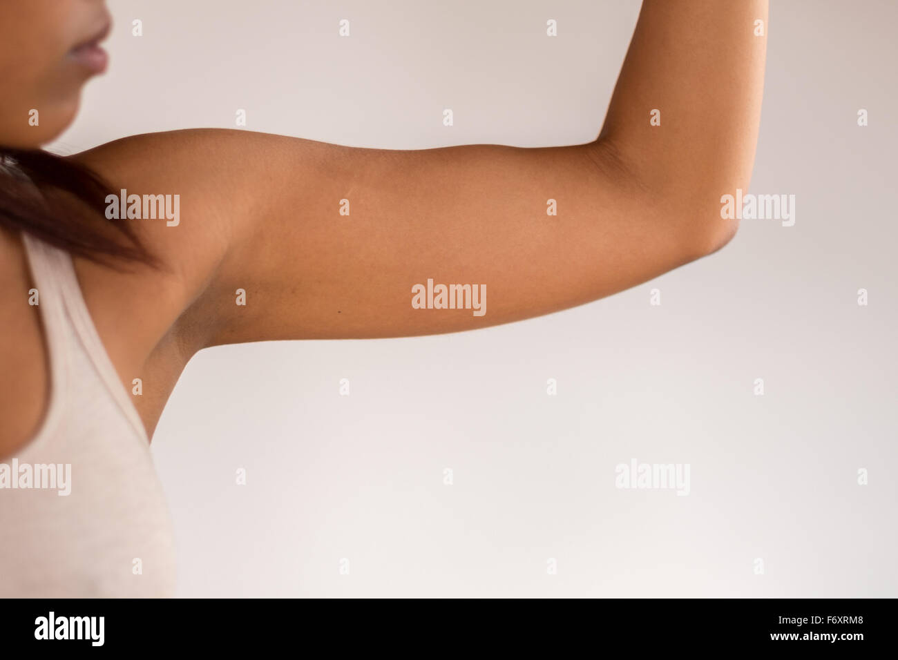Close up Athletic giovane donna afro-americana mostra il suo braccio muscolo contro il muro bianco sullo sfondo. Foto Stock