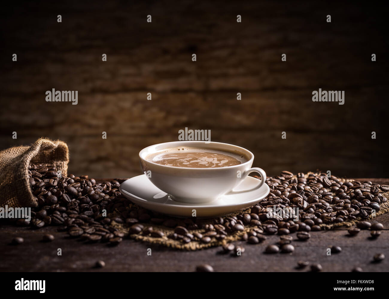 Tazza di caffè con caffè sparsi fagiolini sullo sfondo di legno Foto Stock