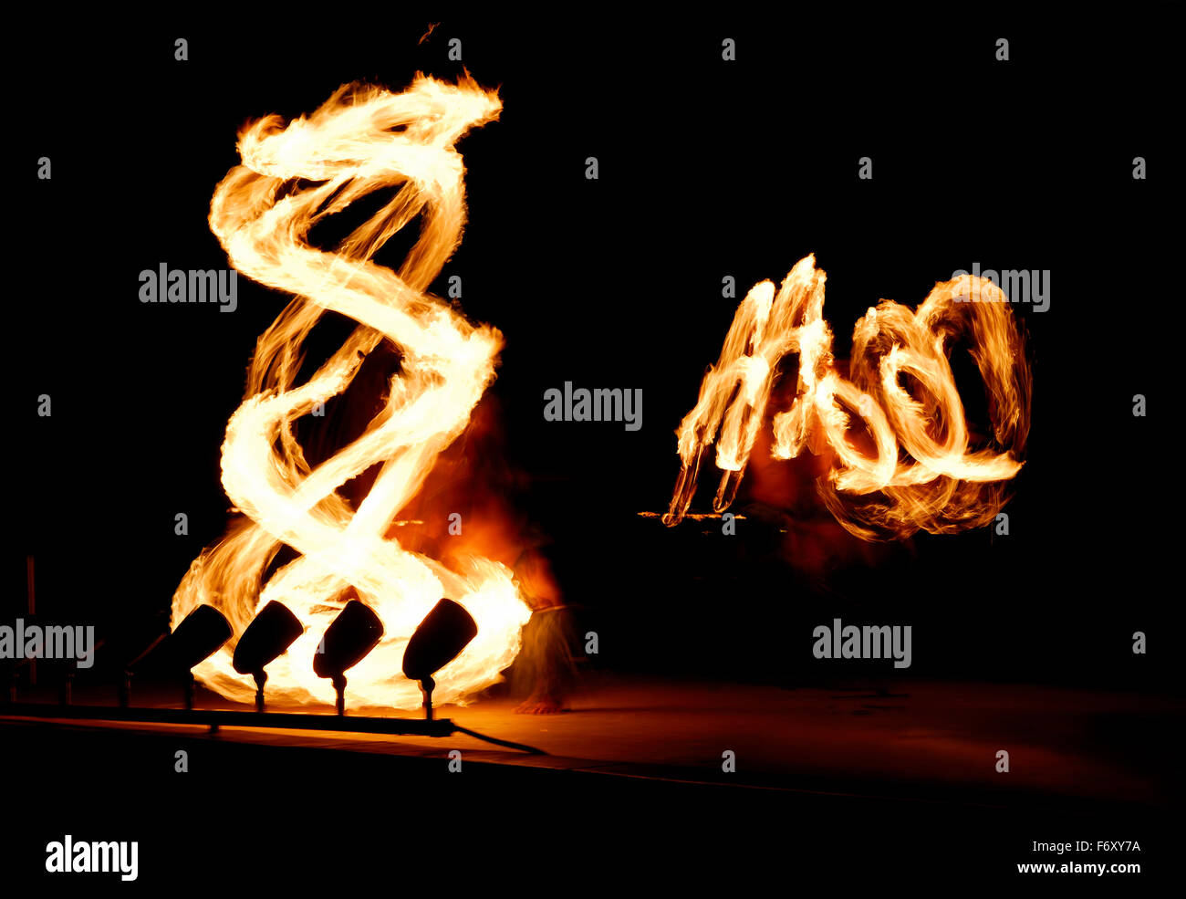 Coppia di ballerini incendio filatura manganelli illuminata di notte dopo un luau Foto Stock