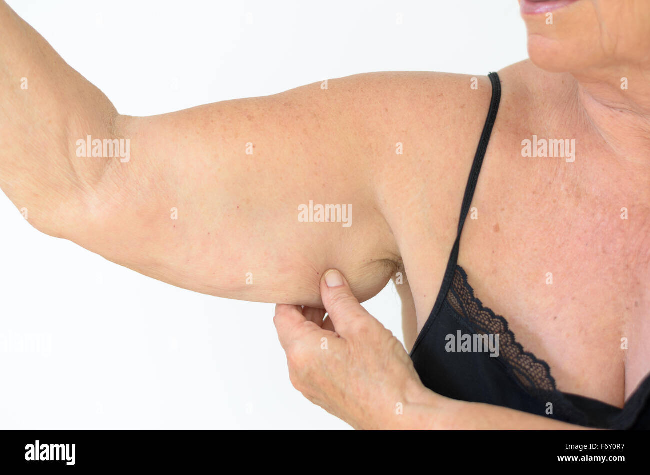Senior donna vestita di nero allacciato bra mentre mostra il braccio floscia, effetto dell'invecchiamento causato dalla perdita di elasticità e muscolo, close-up Foto Stock