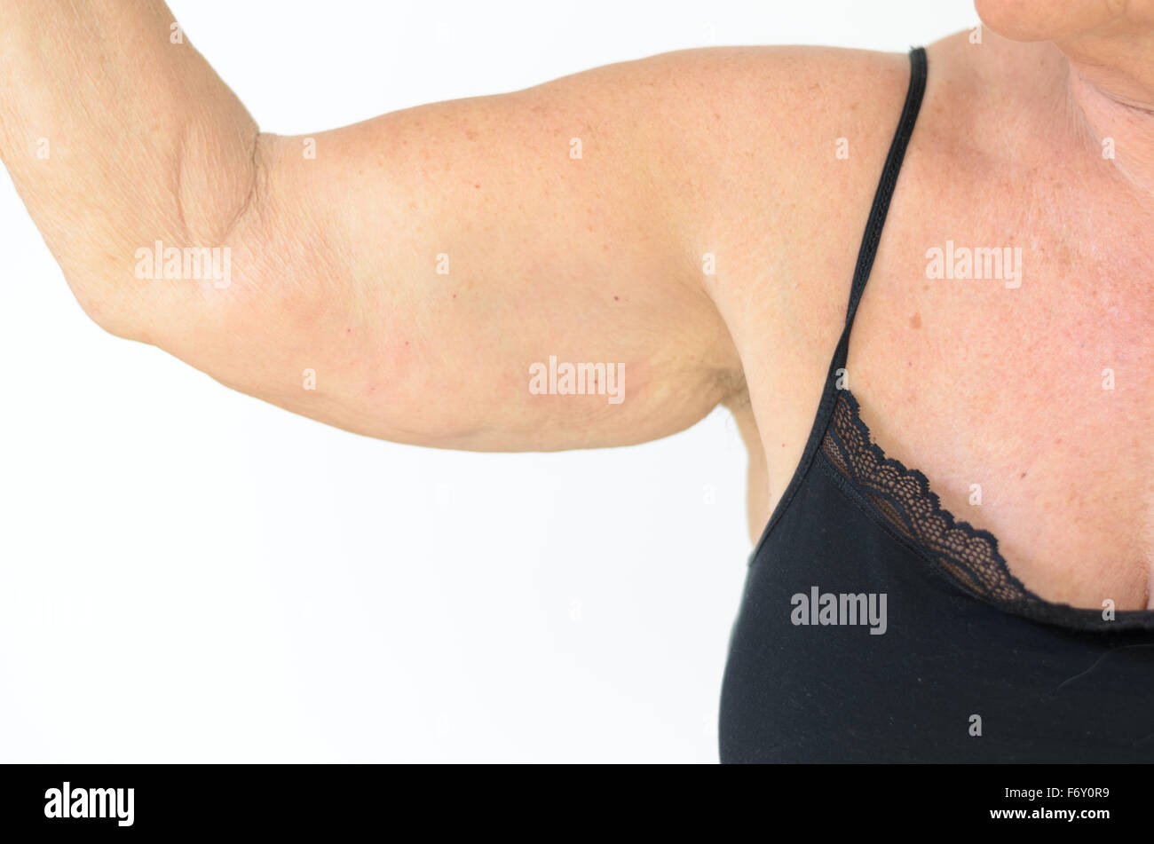 Senior donna vestita di nero allacciato bra mentre mostra il braccio floscia, effetto dell'invecchiamento causato dalla perdita di elasticità e muscolo, close-up Foto Stock
