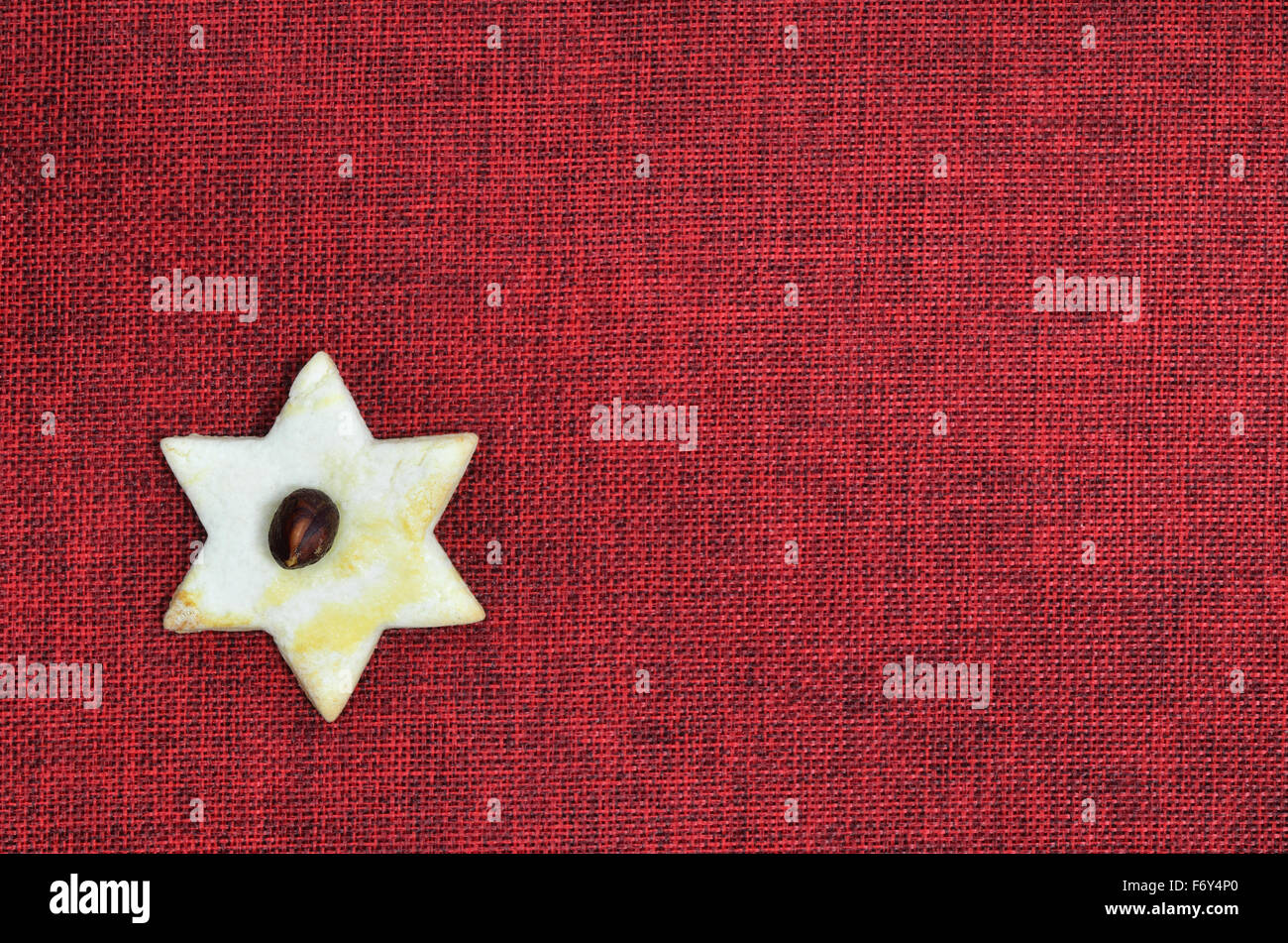 Close up di un cookie di Natale , forma di stella e con granella di nocciole, su tela rossa con spazio copia, orizzontale Foto Stock